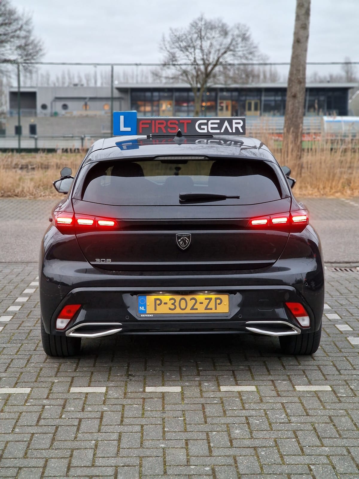 De lesauto van Rijschool First Gear van achteren.